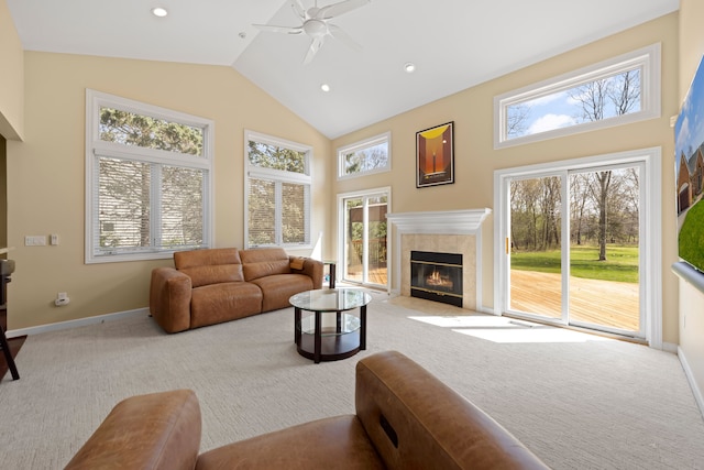 carpeted living room with a tile fireplace, a ceiling fan, high vaulted ceiling, and a healthy amount of sunlight