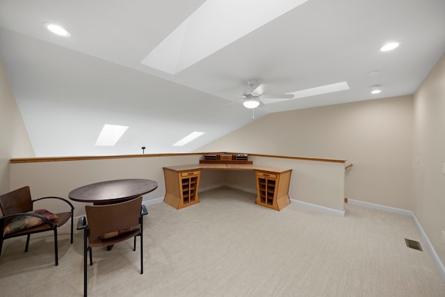 unfurnished office with recessed lighting, vaulted ceiling with skylight, light carpet, visible vents, and a ceiling fan