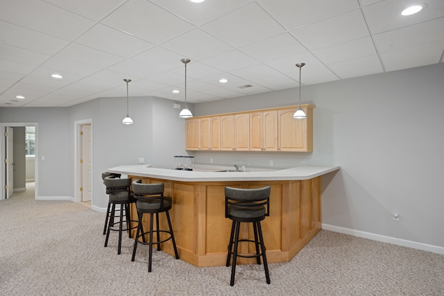 kitchen featuring a breakfast bar, baseboards, light brown cabinets, and light colored carpet