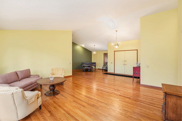 living area with light wood-style floors, vaulted ceiling, baseboards, and an inviting chandelier