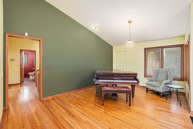 sitting room with high vaulted ceiling, baseboards, and light wood-style flooring