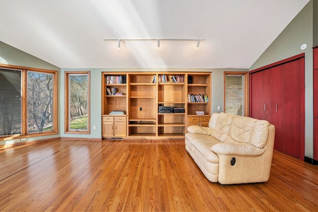 living area with light wood-style floors, lofted ceiling, and rail lighting