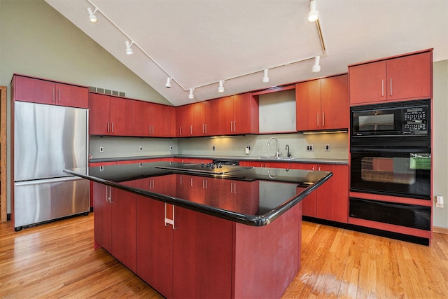 kitchen with a sink, a warming drawer, dark countertops, rail lighting, and black appliances