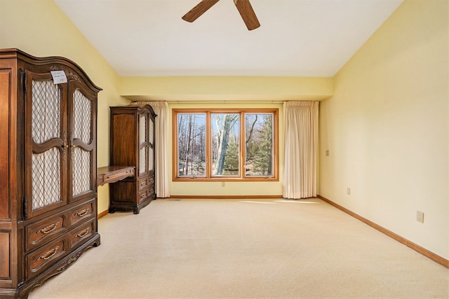 carpeted empty room featuring baseboards and a ceiling fan