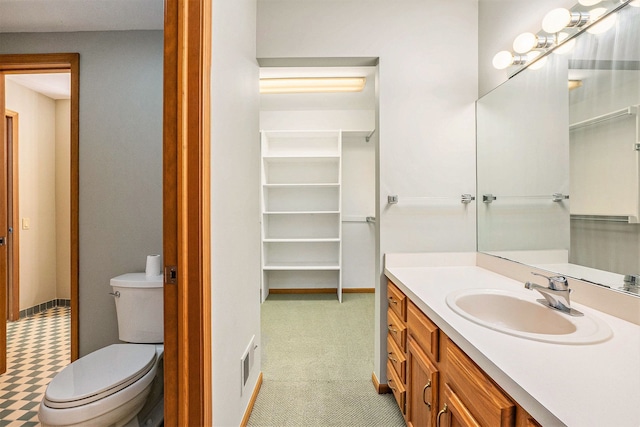 full bath with a spacious closet, visible vents, toilet, vanity, and baseboards