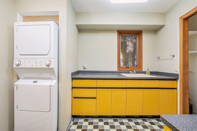 laundry area featuring stacked washing maching and dryer, tile patterned floors, laundry area, and a sink