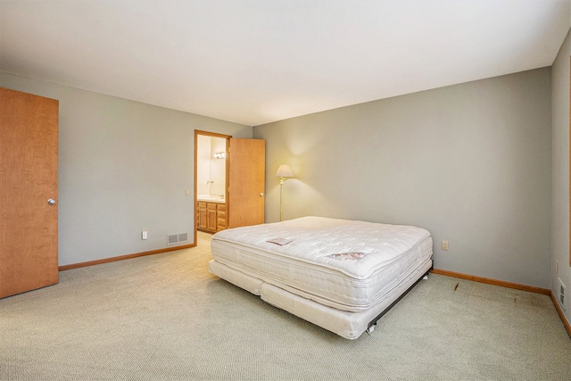carpeted bedroom featuring visible vents, baseboards, and ensuite bathroom