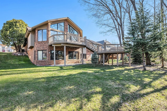 back of property with a wooden deck, a lawn, brick siding, and stairs