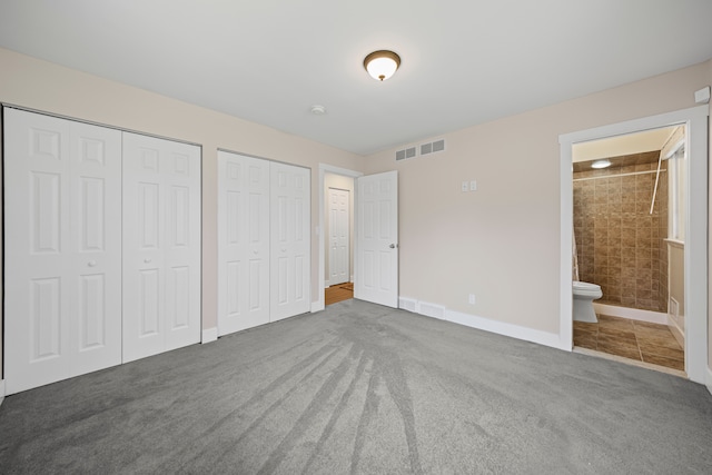 unfurnished bedroom with visible vents, baseboards, two closets, connected bathroom, and carpet flooring
