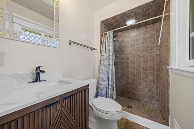 bathroom featuring vanity, tile patterned flooring, a tile shower, and toilet