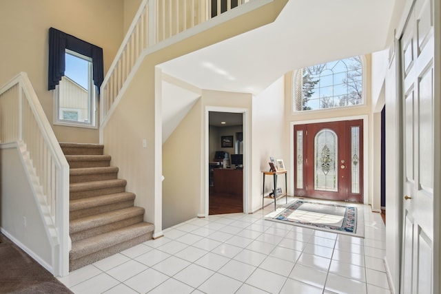 entrance foyer with a wealth of natural light, stairway, and a towering ceiling