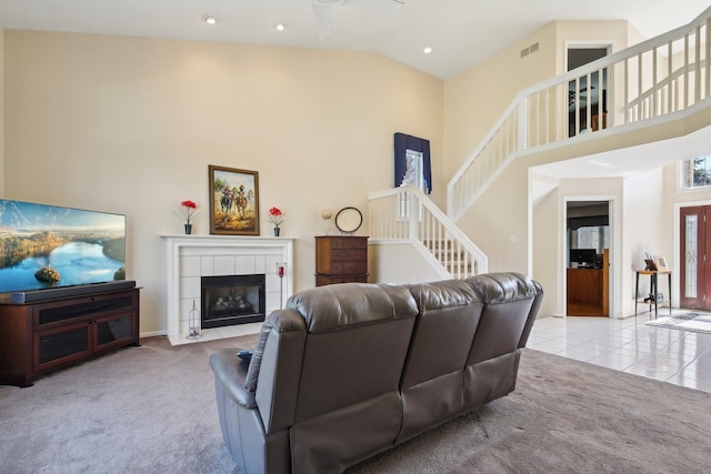 carpeted living room featuring visible vents, stairs, a tile fireplace, high vaulted ceiling, and recessed lighting