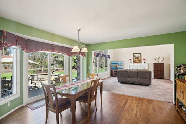 dining space featuring baseboards, an inviting chandelier, and wood finished floors