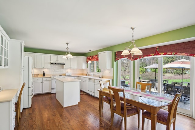 kitchen with a kitchen island, white appliances, under cabinet range hood, white cabinets, and a notable chandelier