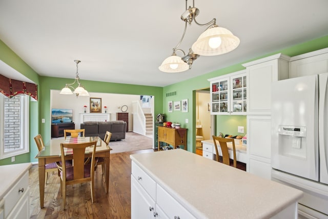 kitchen with visible vents, light countertops, dark wood-style flooring, and white refrigerator with ice dispenser