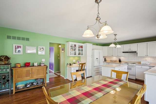 dining area featuring an inviting chandelier, baseboards, dark wood-style flooring, and visible vents