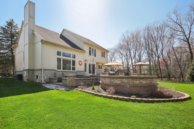 rear view of house with a lawn, a shingled roof, a chimney, and central AC