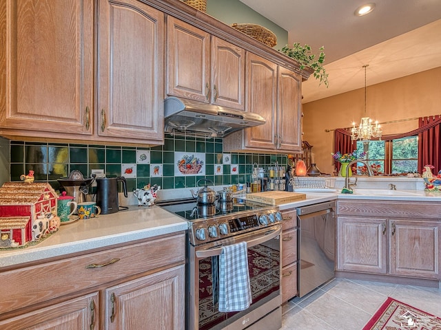 kitchen featuring stainless steel appliances, a sink, tasteful backsplash, a notable chandelier, and under cabinet range hood