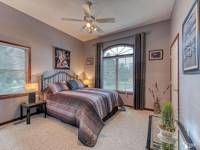 bedroom with ceiling fan, light carpet, a textured wall, and baseboards