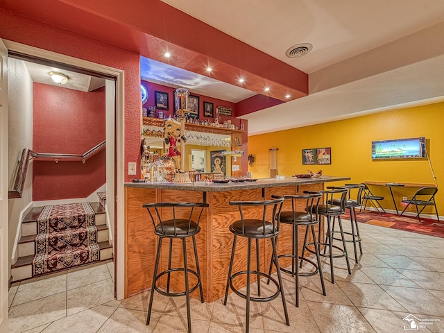 bar with visible vents, baseboards, and indoor wet bar