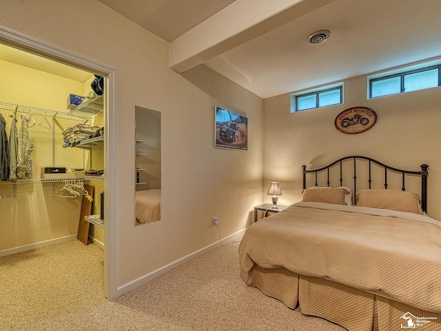 carpeted bedroom featuring baseboards, visible vents, and a walk in closet