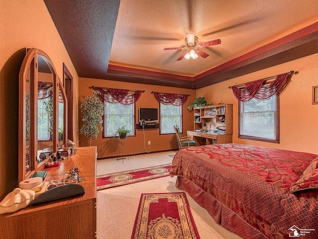 carpeted bedroom featuring a ceiling fan, a textured ceiling, and a raised ceiling