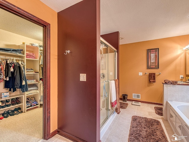 full bathroom with a bath, a textured ceiling, visible vents, a spacious closet, and a shower stall