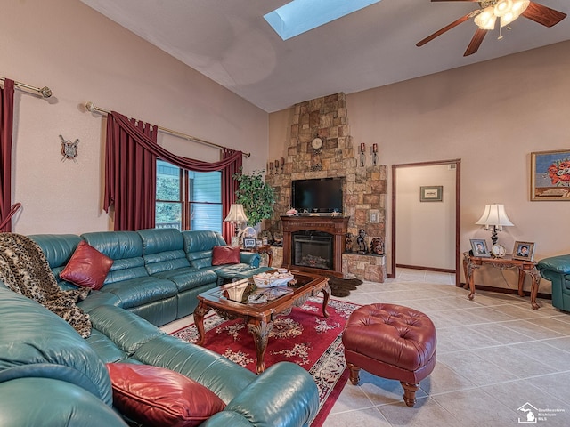 living area with a ceiling fan, light tile patterned floors, a large fireplace, a skylight, and high vaulted ceiling