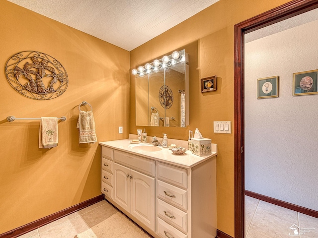 bathroom with tile patterned flooring, baseboards, vanity, and a textured ceiling