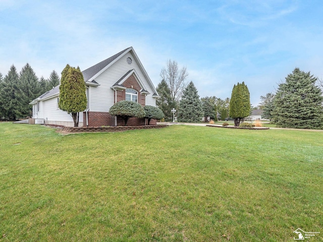 view of side of home featuring brick siding and a yard