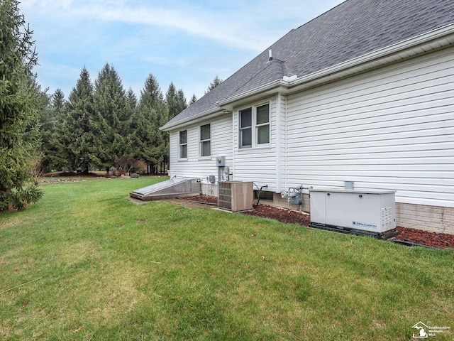 rear view of property with central AC unit, roof with shingles, and a yard