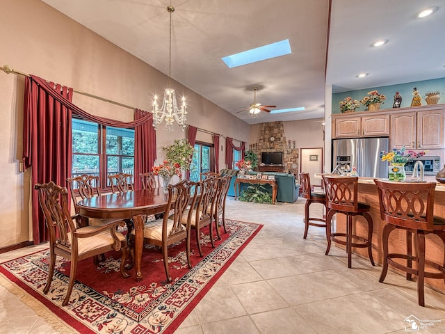 dining room with recessed lighting, vaulted ceiling with skylight, ceiling fan with notable chandelier, and light tile patterned floors