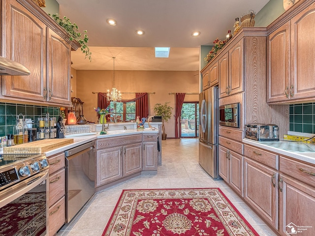 kitchen featuring stainless steel appliances, a peninsula, recessed lighting, a notable chandelier, and decorative backsplash