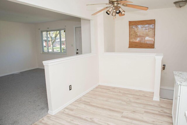 empty room featuring light wood finished floors, baseboards, and ceiling fan