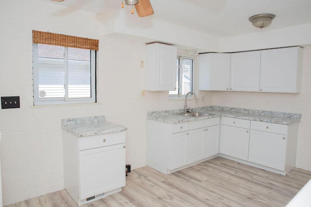 kitchen with light wood-type flooring, a ceiling fan, white cabinets, and a sink
