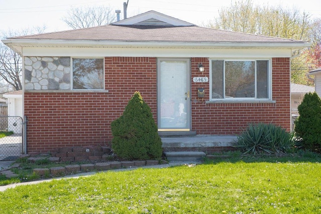bungalow-style home featuring brick siding, fence, and a front yard