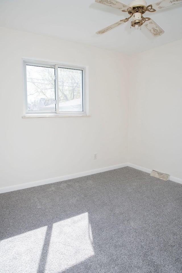 spare room featuring carpet floors, visible vents, baseboards, and ceiling fan