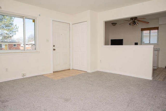 interior space featuring baseboards, carpet flooring, ceiling fan, and a healthy amount of sunlight