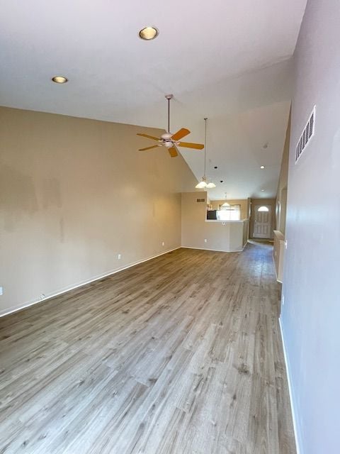 unfurnished living room with light wood-style floors, visible vents, a ceiling fan, and baseboards