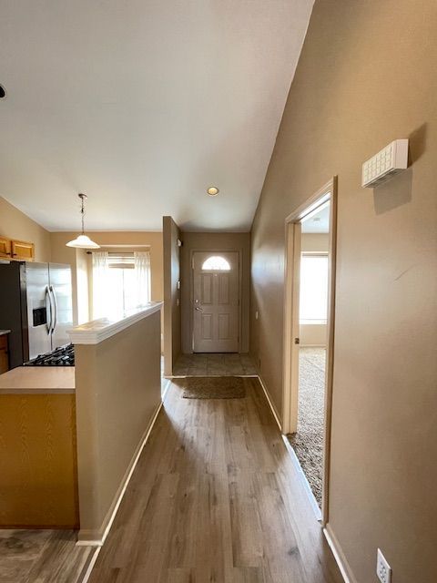 entryway with lofted ceiling, baseboards, and wood finished floors