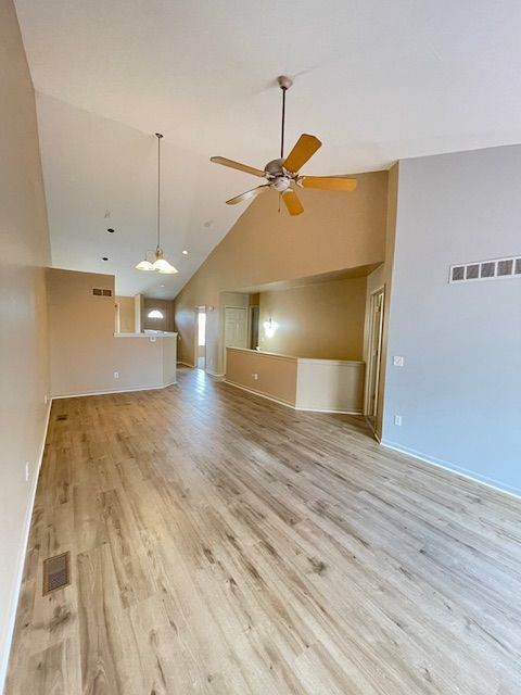 unfurnished living room featuring light wood finished floors, baseboards, a ceiling fan, and visible vents