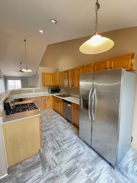 kitchen with light countertops, decorative light fixtures, stainless steel appliances, and a sink