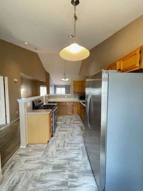 kitchen with vaulted ceiling, hanging light fixtures, light countertops, a peninsula, and appliances with stainless steel finishes