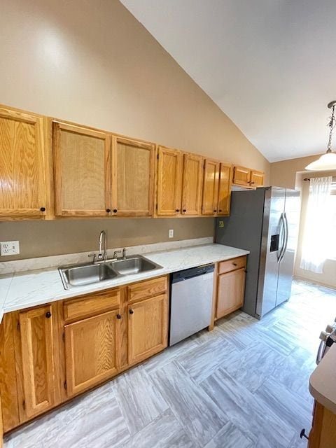 kitchen featuring light countertops, vaulted ceiling, a sink, decorative light fixtures, and appliances with stainless steel finishes
