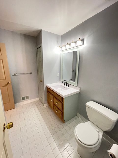 bathroom featuring tile patterned floors, visible vents, toilet, vanity, and baseboards