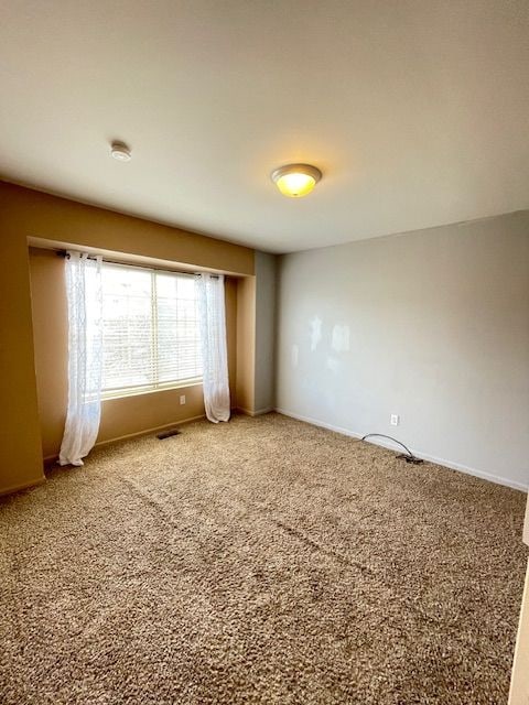carpeted spare room with baseboards and visible vents
