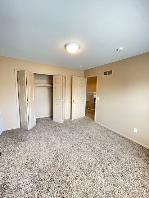 unfurnished bedroom featuring a closet, visible vents, carpet flooring, and baseboards