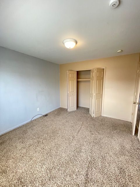 unfurnished bedroom featuring a closet, carpet flooring, and baseboards
