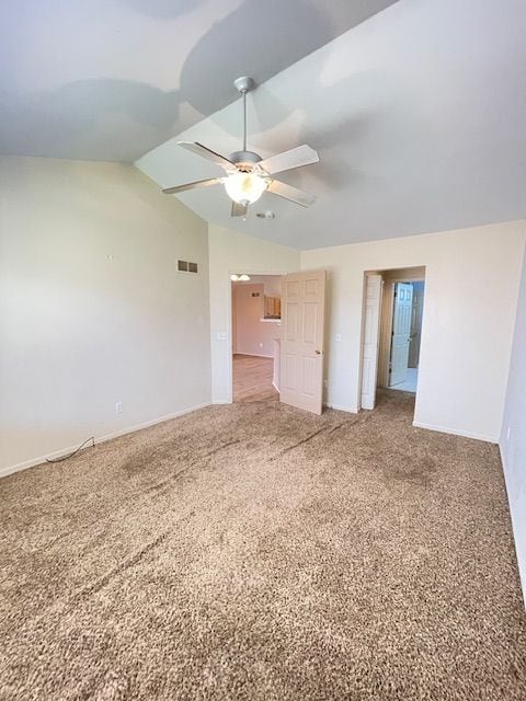 spare room featuring lofted ceiling, baseboards, a ceiling fan, and visible vents