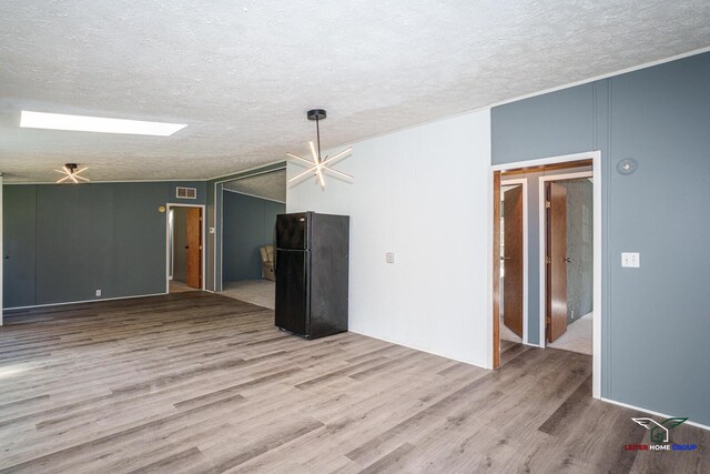 unfurnished living room with visible vents, a textured ceiling, and wood finished floors